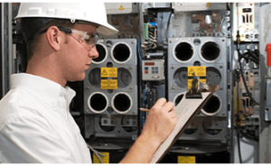 Man wearing a heavy-duty hard hat inspecting and performing preventive maintenance on a system