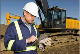 Engineer inspecting building progress with excavators in the background