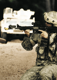 A soldier arming a gun with a tank in the background